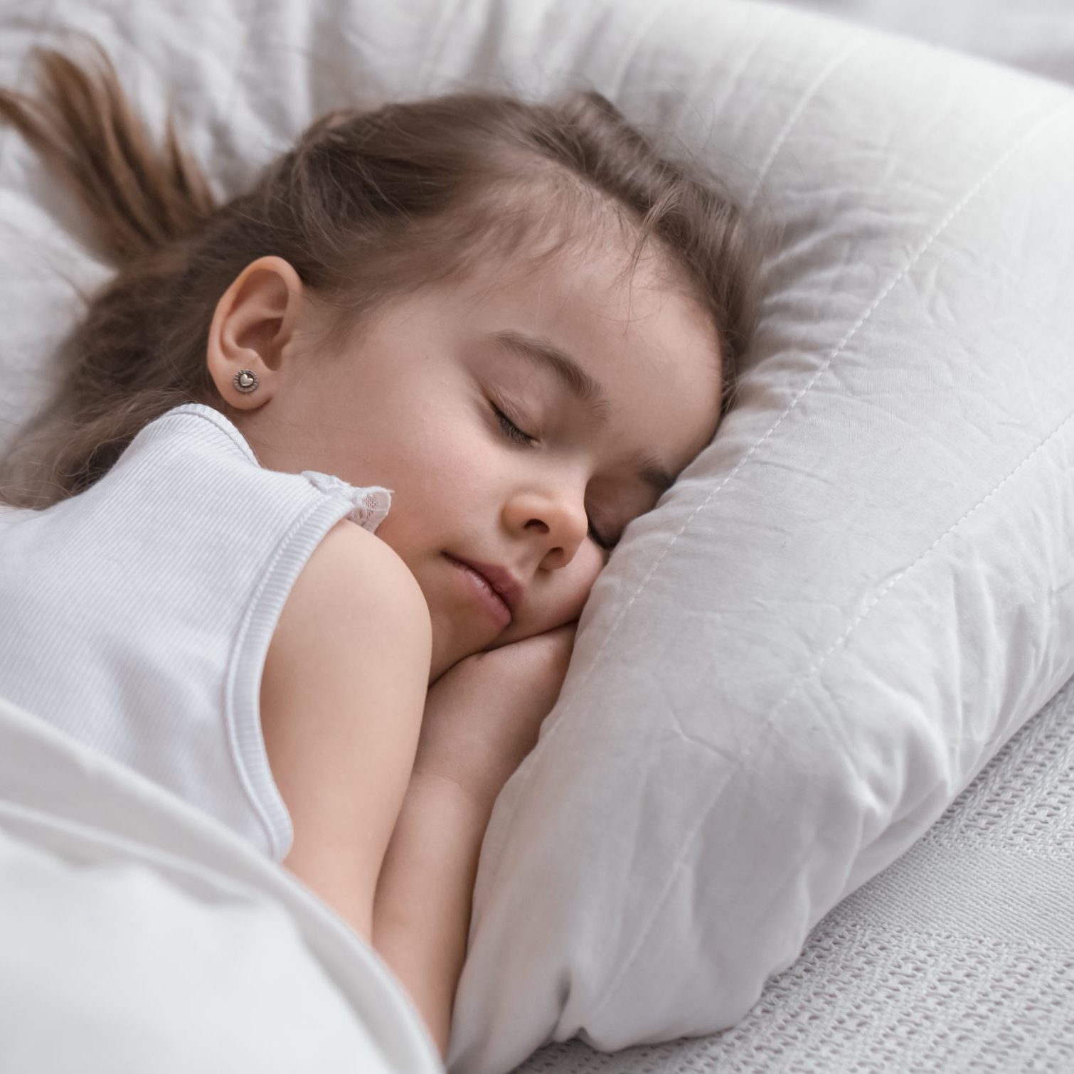 Cute little girl sleeps sweetly in a white cozy bed, the concept of children's rest and sleep